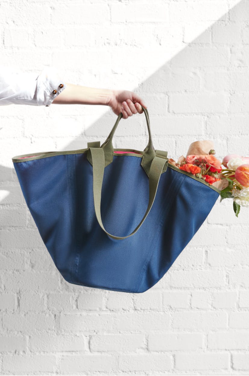 The Reversible Tote in Navy & Pink held by a model with flowers inside.