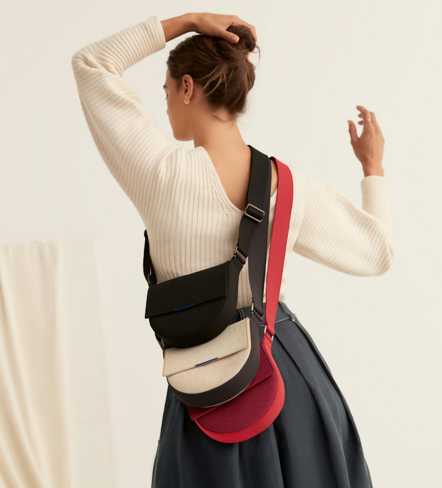 The Saddle Bag in Total Black, Ink and Ivory and Ruby Red shown on-model.