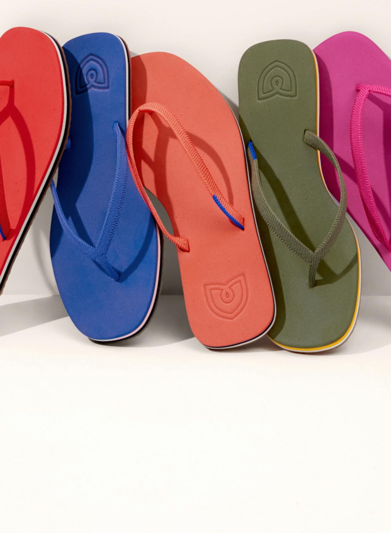 Five individual The Flip sandals lined up against a wall.