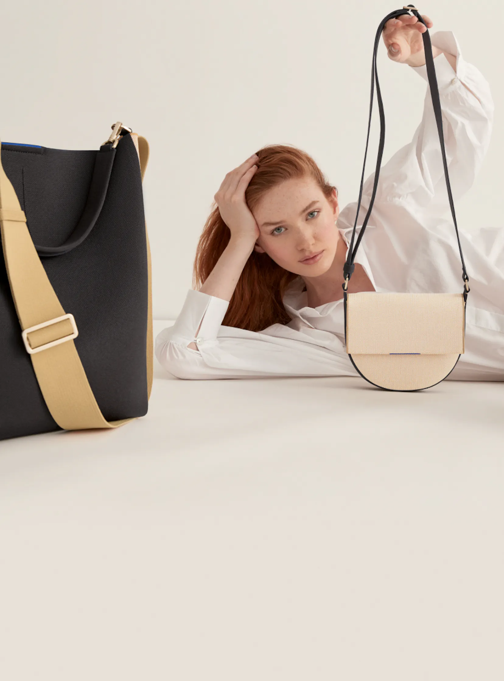 The Bucket Bag in Ink & Ivory, The Saddle Bag in Ink & Ivory and The Essential Tote in Ink & Ivory shown with a model. 
