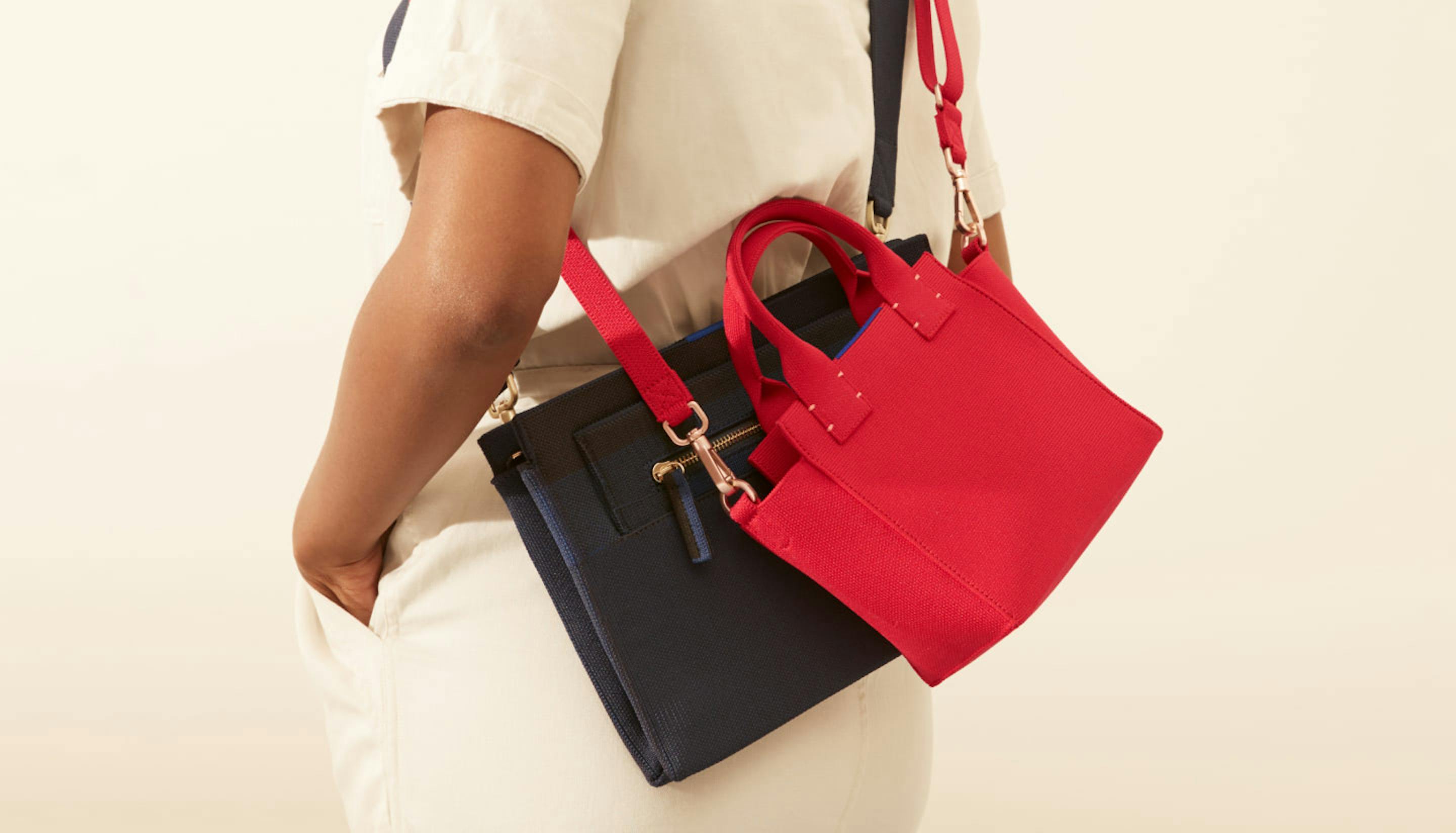 The Dual-Zip Crossbody in Slate Black and The Mini Handbag in Candy Apple shown on model.