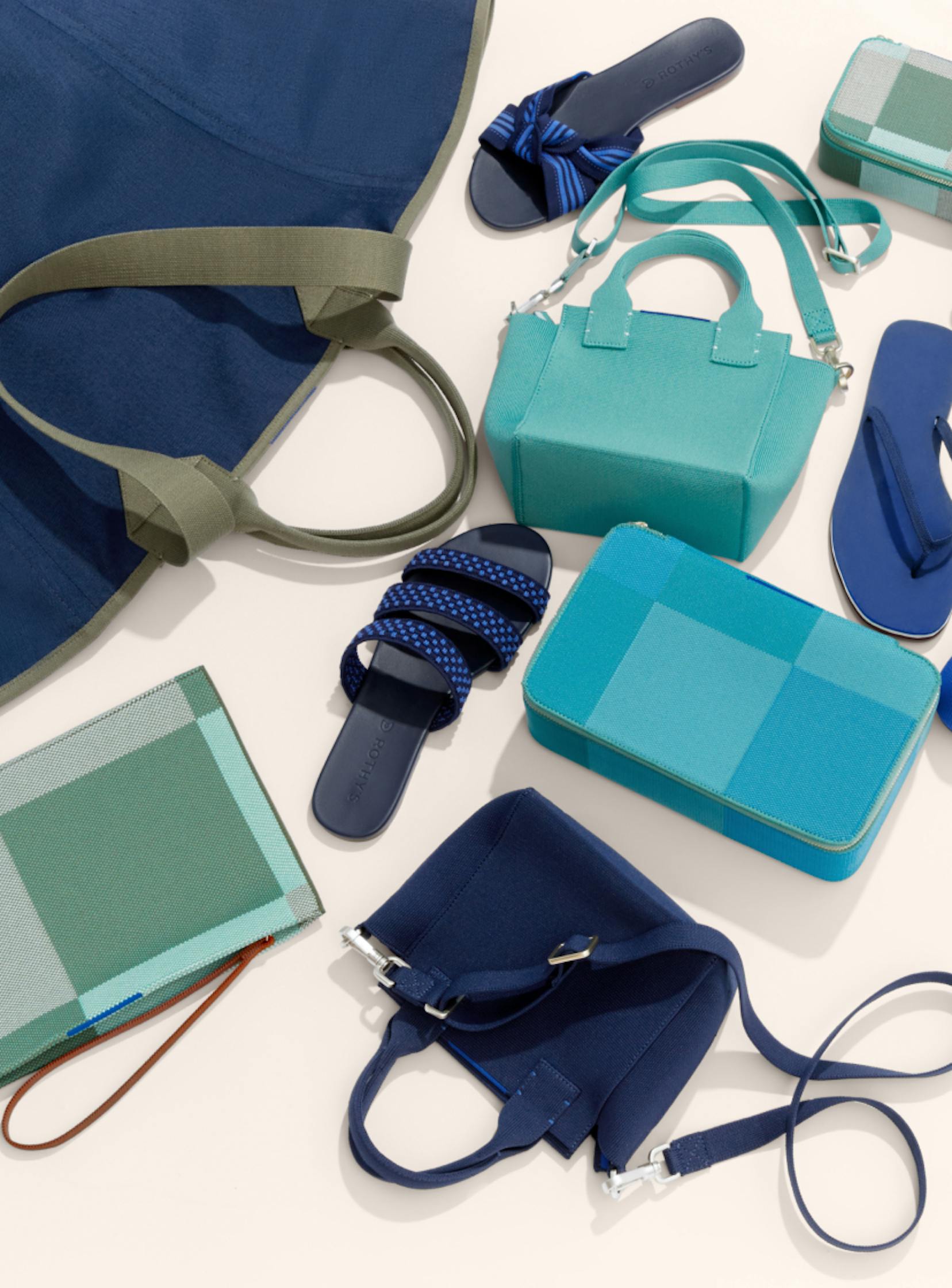 A laydown of The Reversible Tote in Navy & Pink, The Mini Handbag in Juniper Green, The Mini Catchall in Juniper Madras, The Mid Catchall in Juniper Green, The Large Catchall in Caribbean Madras, The Essential Pouch in Juniper Madras, The Flip in Splash, The Flat in Cornflower, The Knot in Cobalt Stripe and The Triple Band in Cobalt Basket Stitch.