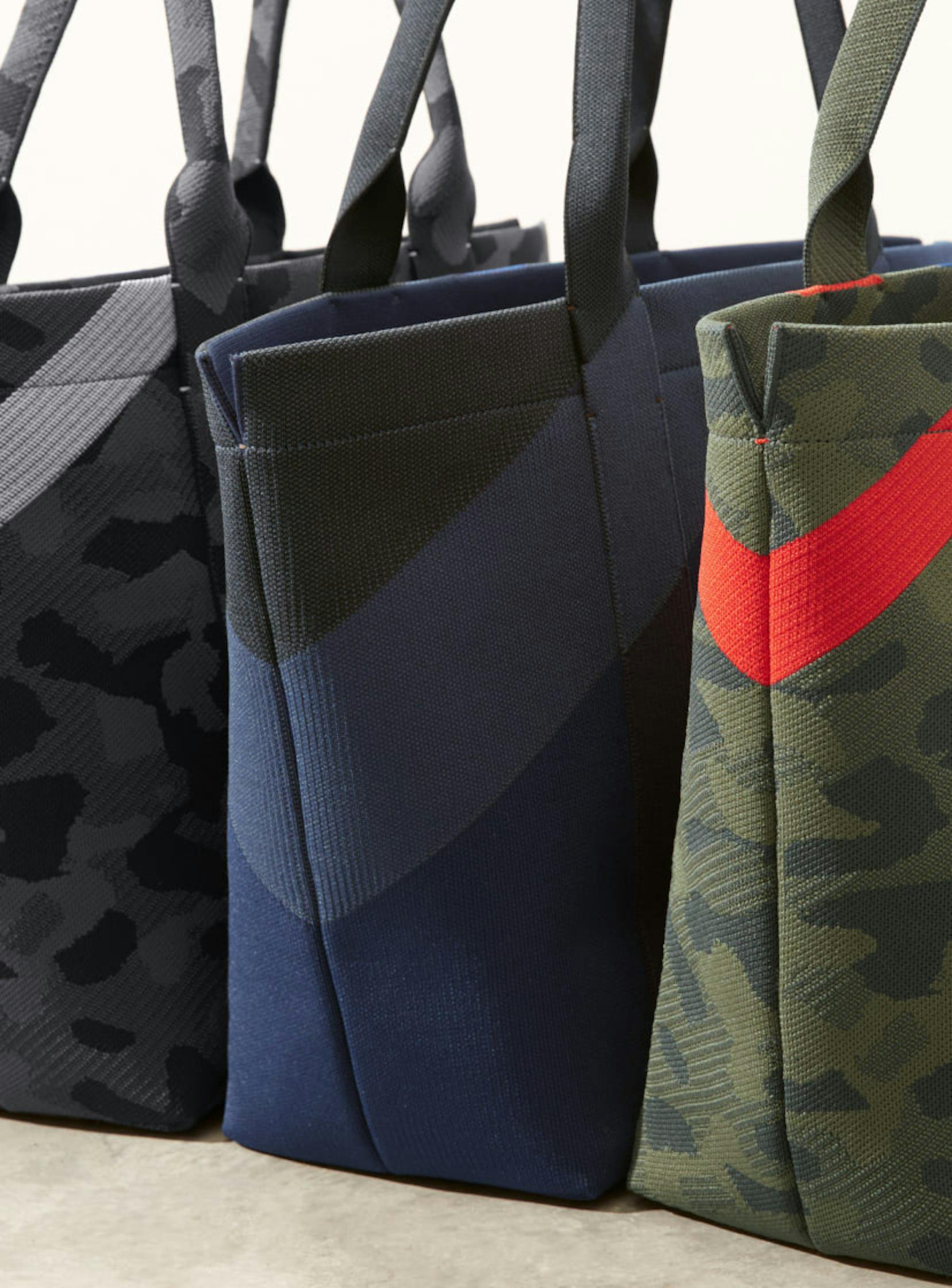 The Essential Tote in Slate Camo, Midnight Navy and Sage Camo shown in diagonal view.