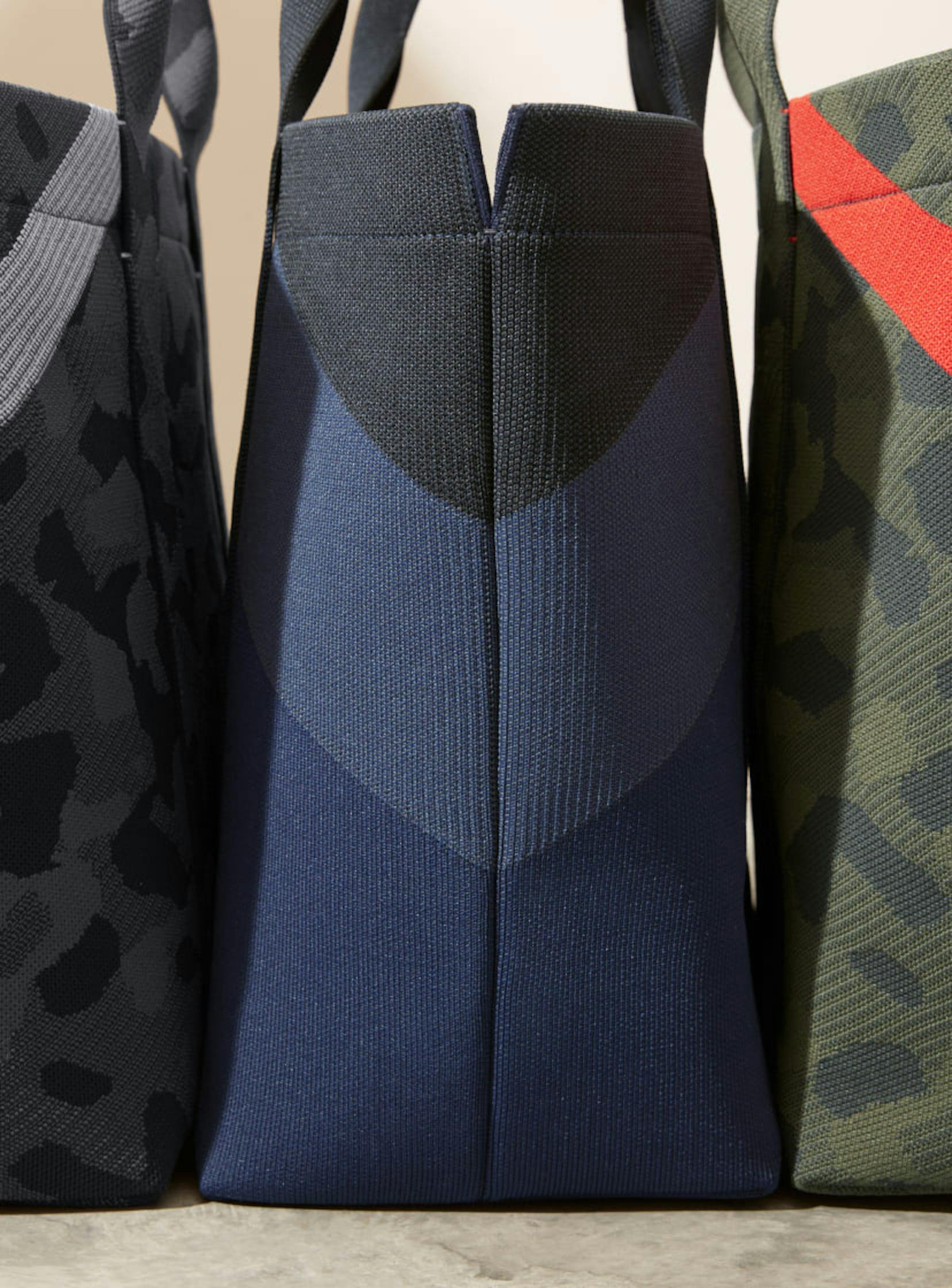 The Essential Tote in Slate Camo, The Essential Tote in Midnight Navy and The Essential Tote in Sage Camo shown close up from the side highlighting the corner color detail.