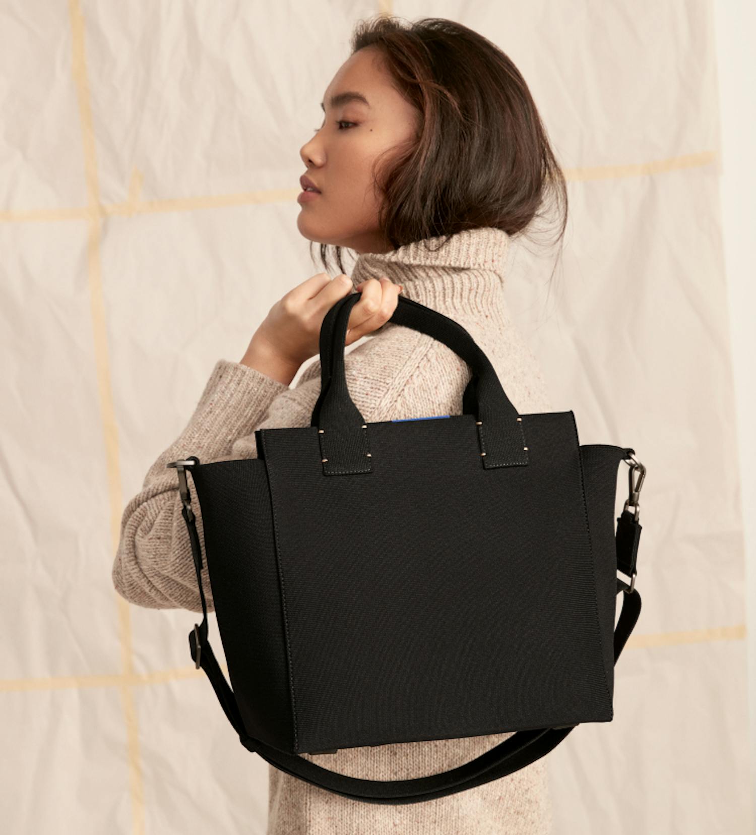 The Handbag in Total Black held by a model.