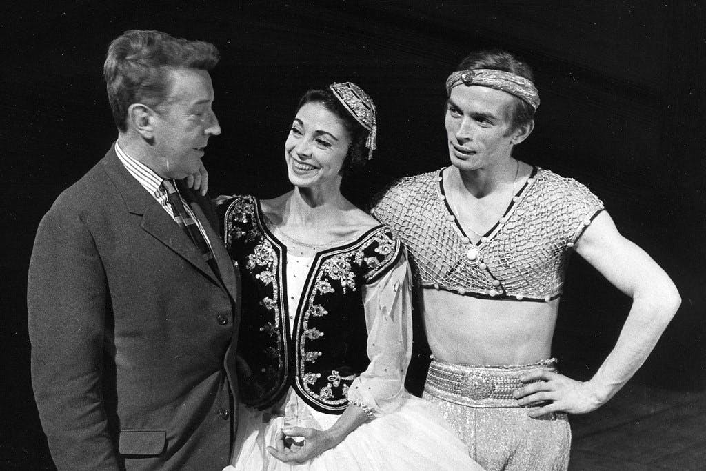 Margot Fonteyn, Rudolf Nureyev and Frederick Ashton  standing together onstage.