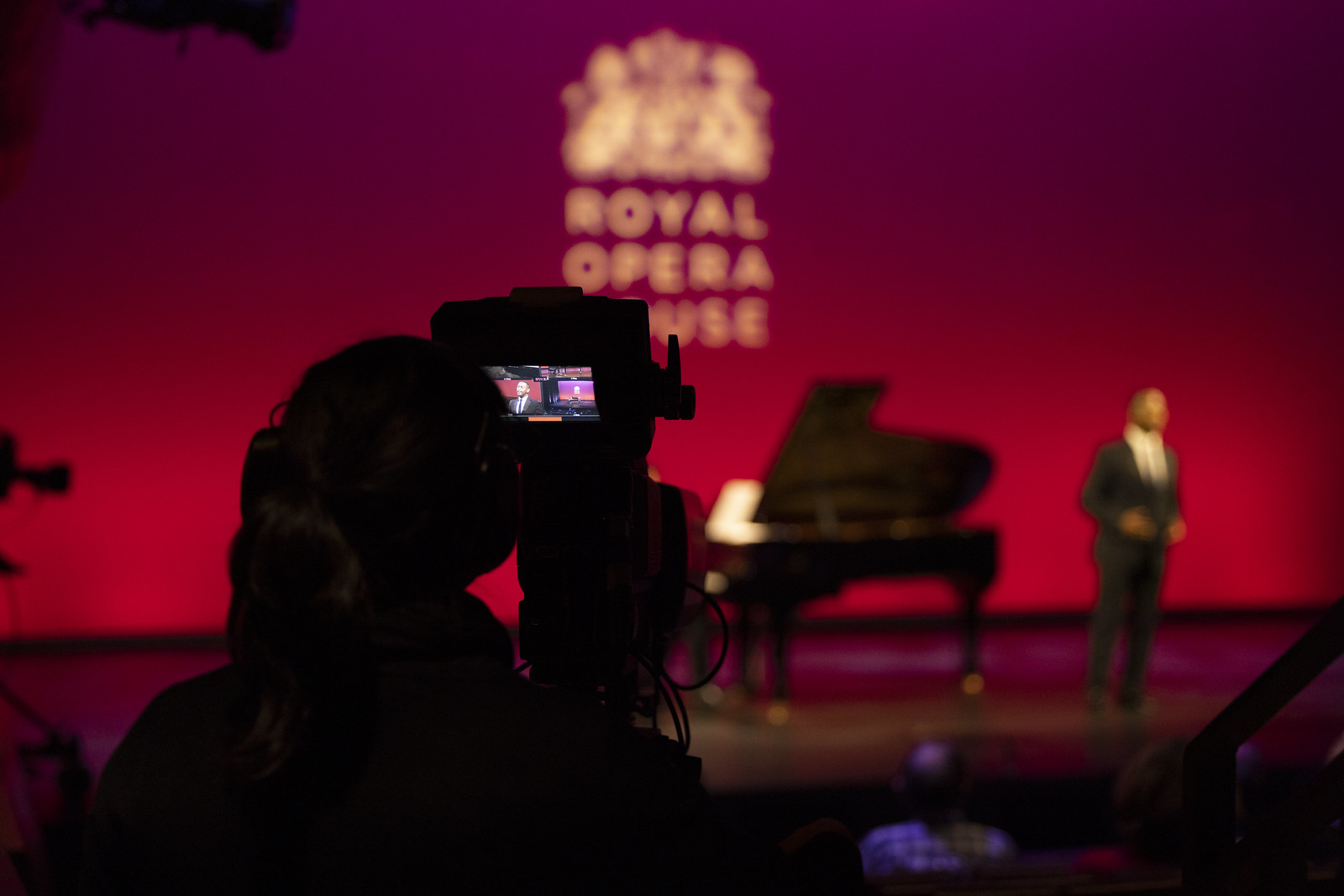 A photographer taking a picture of a singer performing onstage.