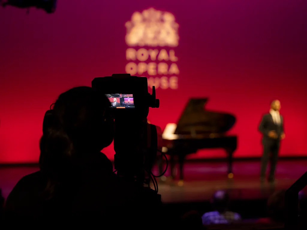 A photographer taking a picture of a singer performing onstage.