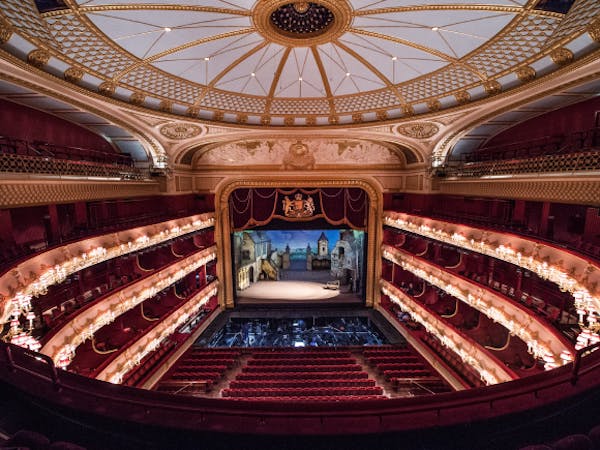 A view looking down at the seating, stage and circular ceiling the auditorium of the Royal Opera House