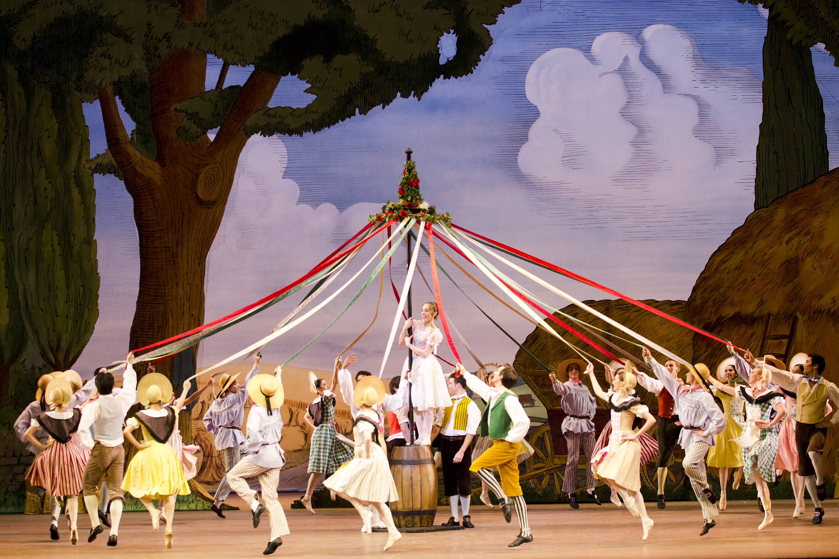 Several dancers skip in a circle holding onto the colourful ribbons of a maypole