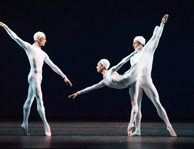 Three dancers in space-suit type costumes perform