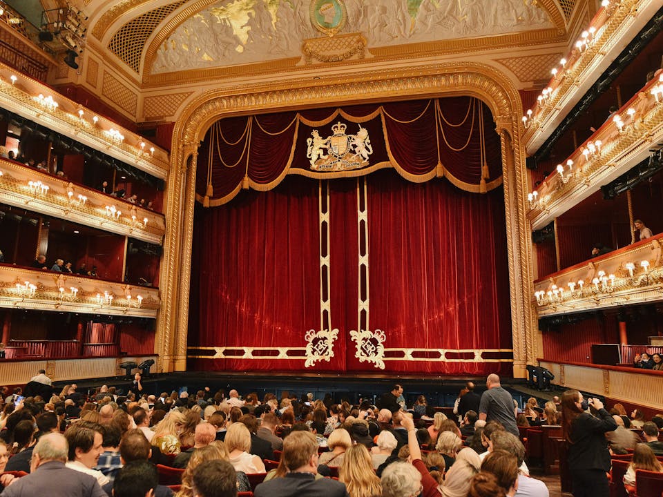 A full audience facing the main stage of the Royal Opera House.