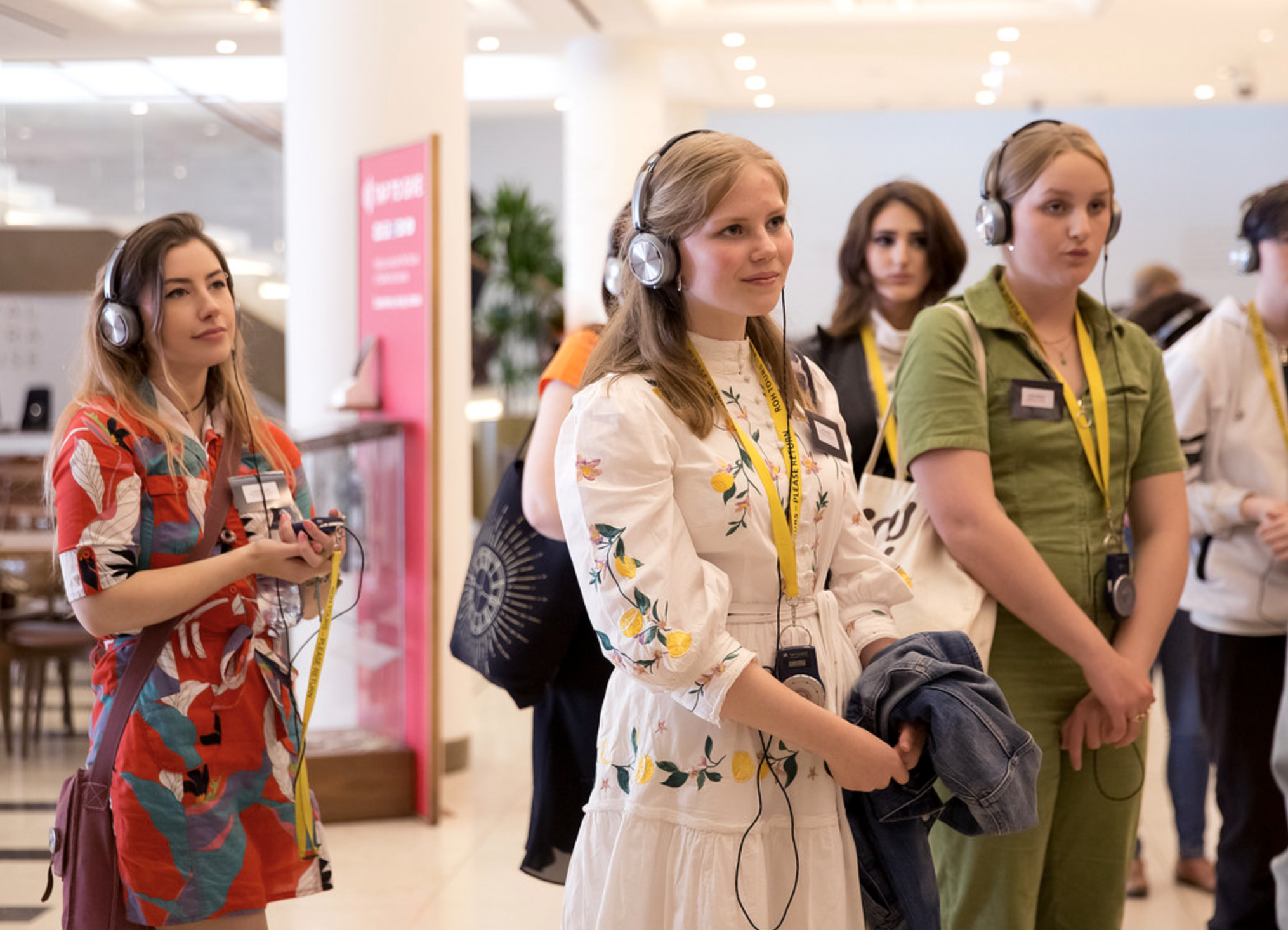 A group of young people wearing headphones while on a tour at the Royal Opera House.