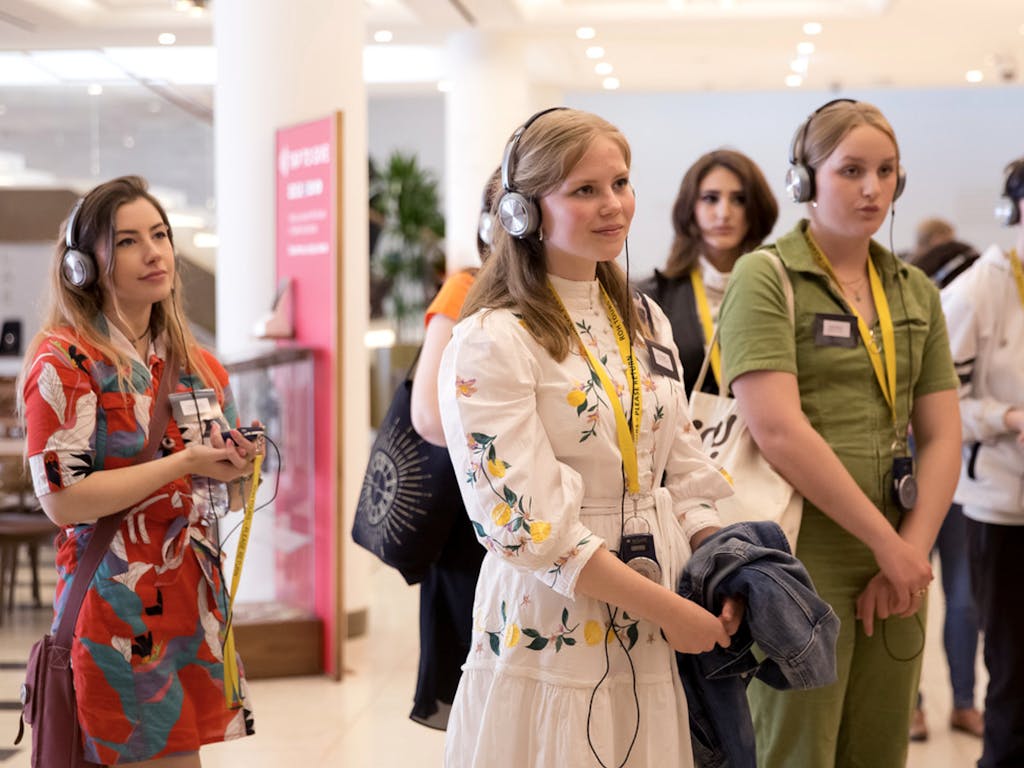 A group of young people wearing headphones while on a tour at the Royal Opera House.
