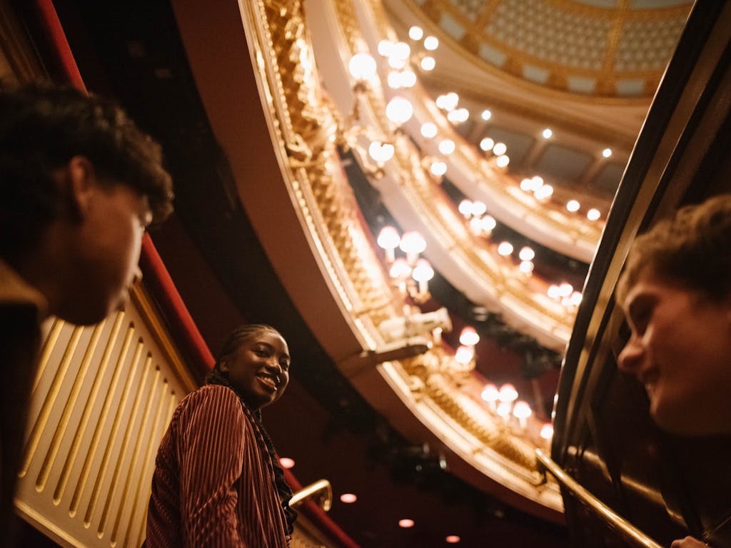Three young people touring the main auditorium of the Royal Opera House.
