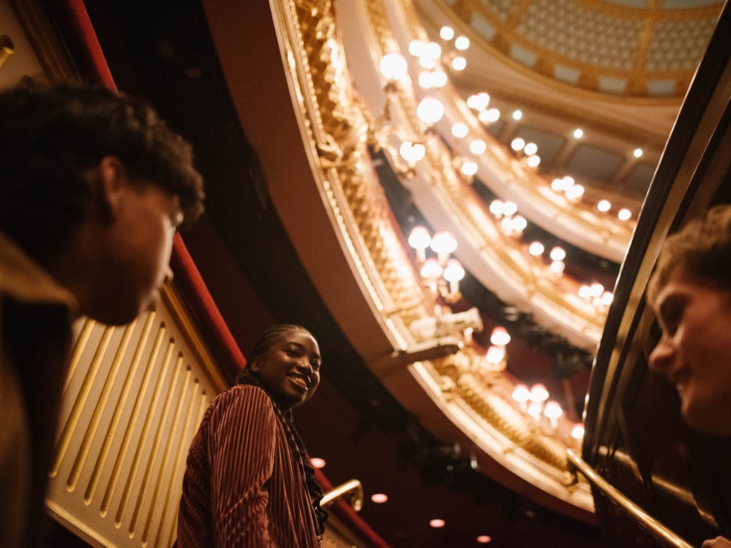 Three young people touring the main auditorium of the Royal Opera House.