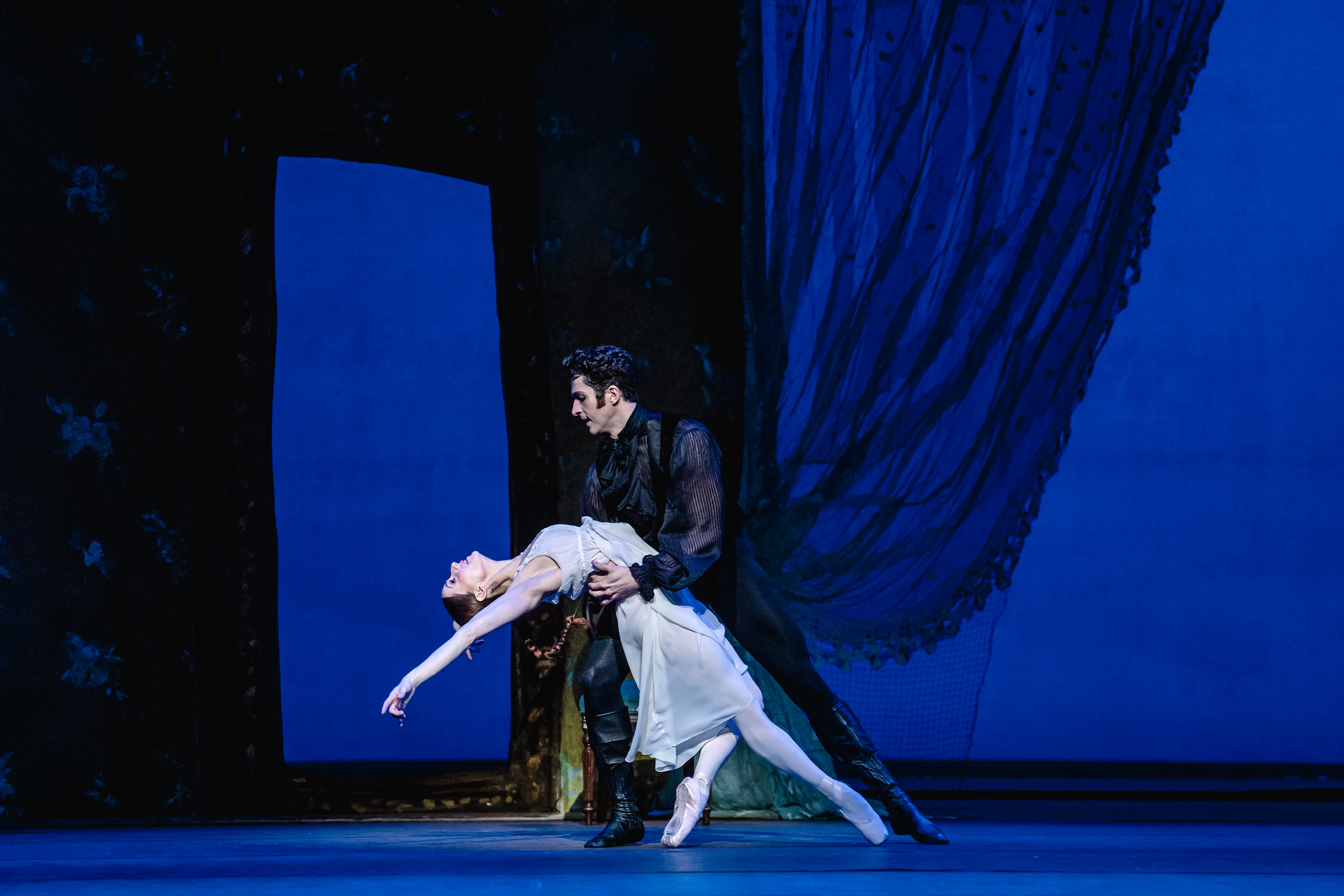 Marianela Nuñez and Reece Clarke as Tatiana Onegin. They are engaged in a passionate duet, with Onegin holding Tatiana's waist as she leans backward, her upper body arched gracefully. 