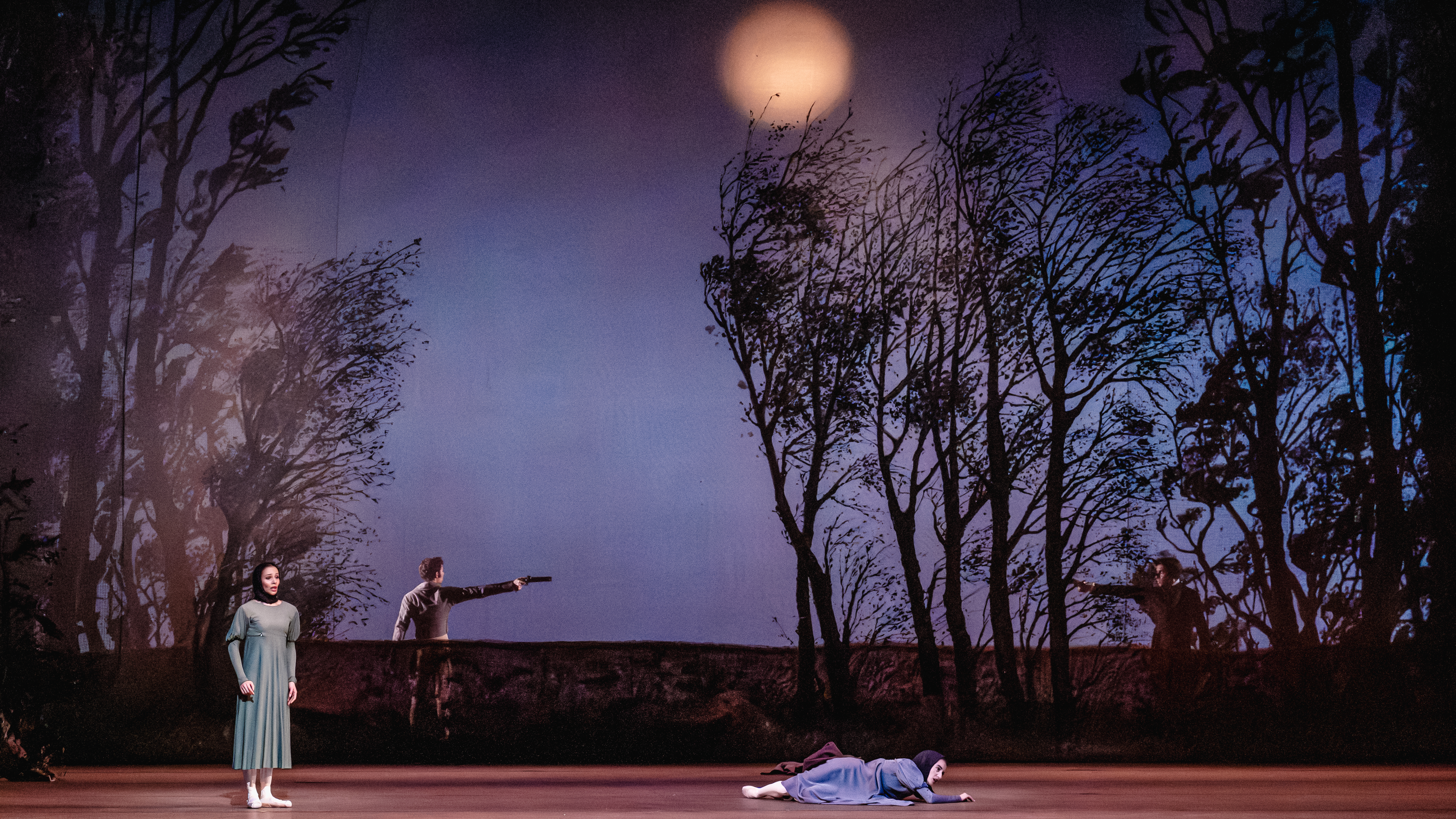 Two women stand in the foreground, despairing, while two men in the background raise their guns at each other. 