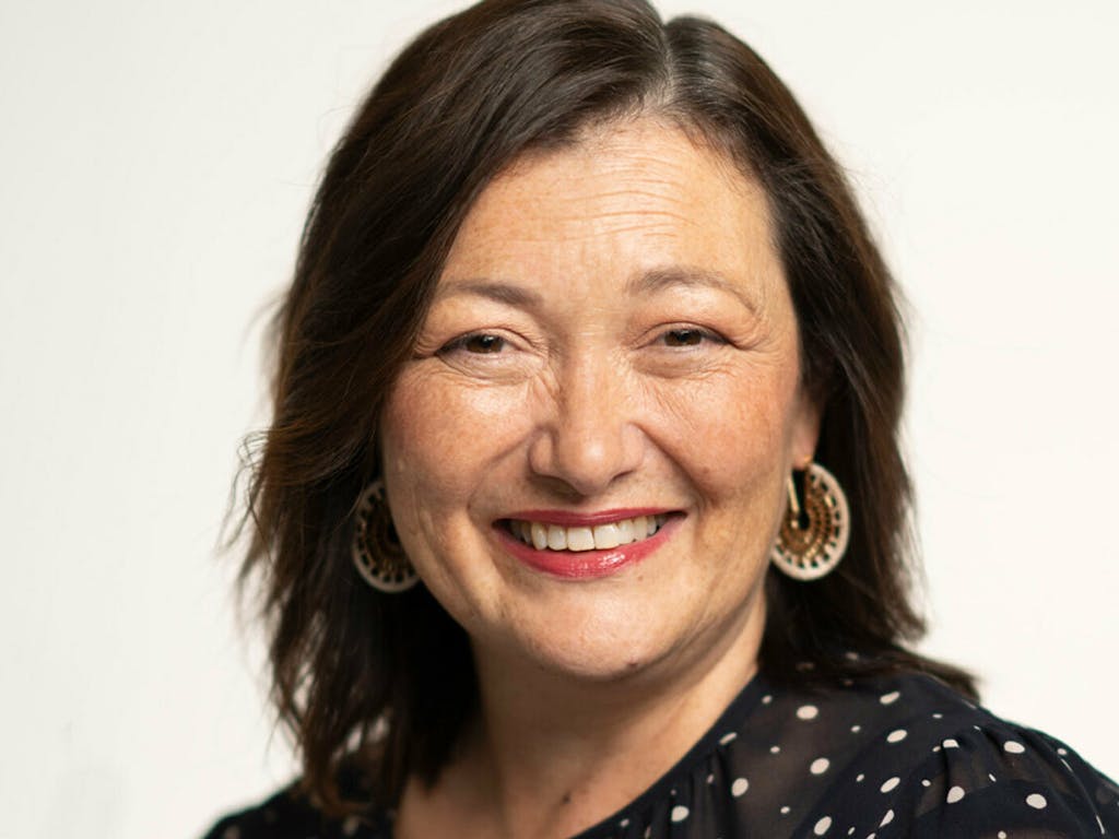 A person with long brown hair smiles at the camera.