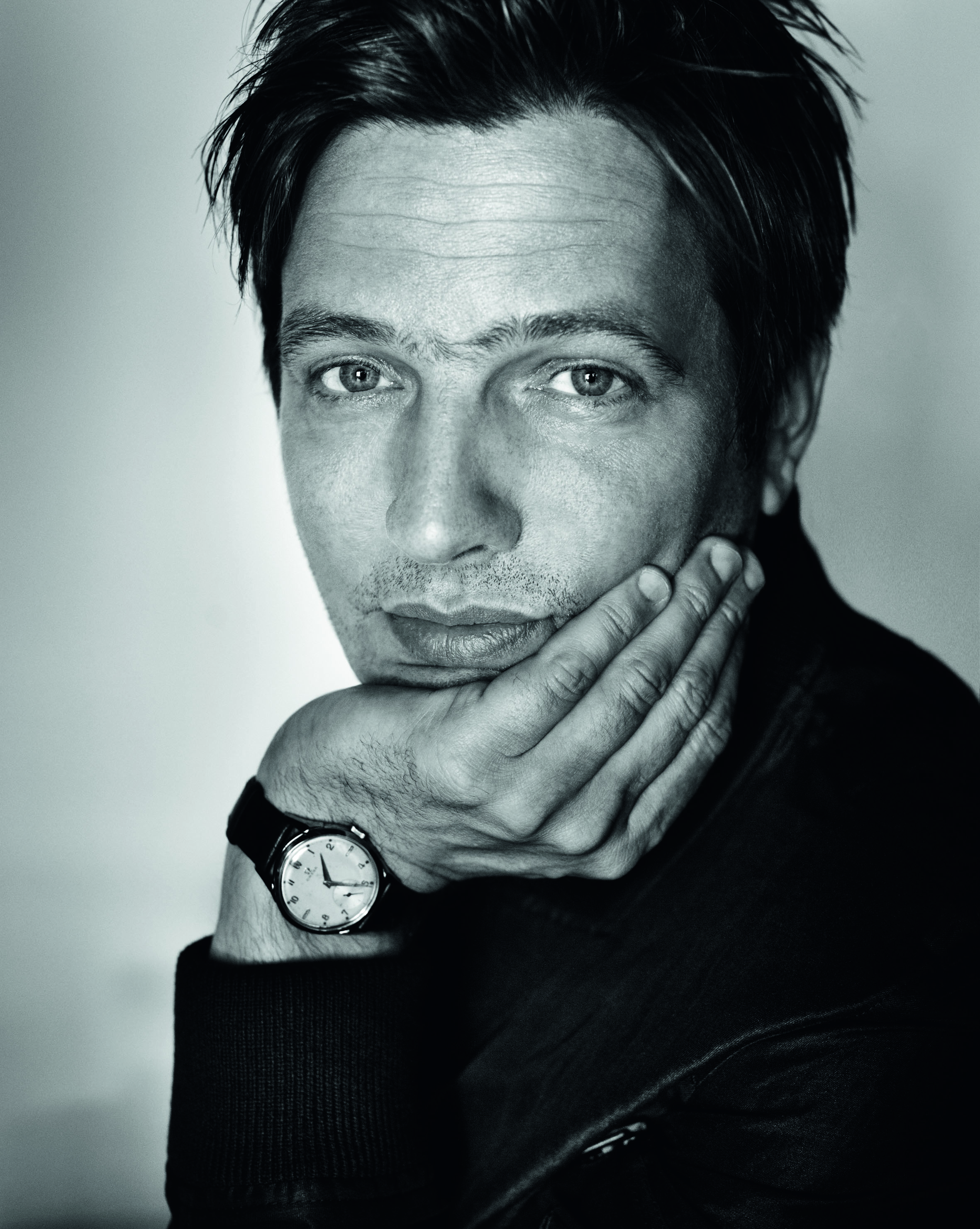 A headshot of Thomas Vinterberg. He is facing the camera and resting his hand on his chin. 