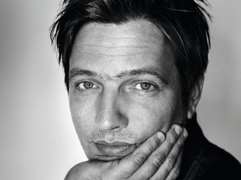 A headshot of Thomas Vinterberg. He is facing the camera and resting his hand on his chin.