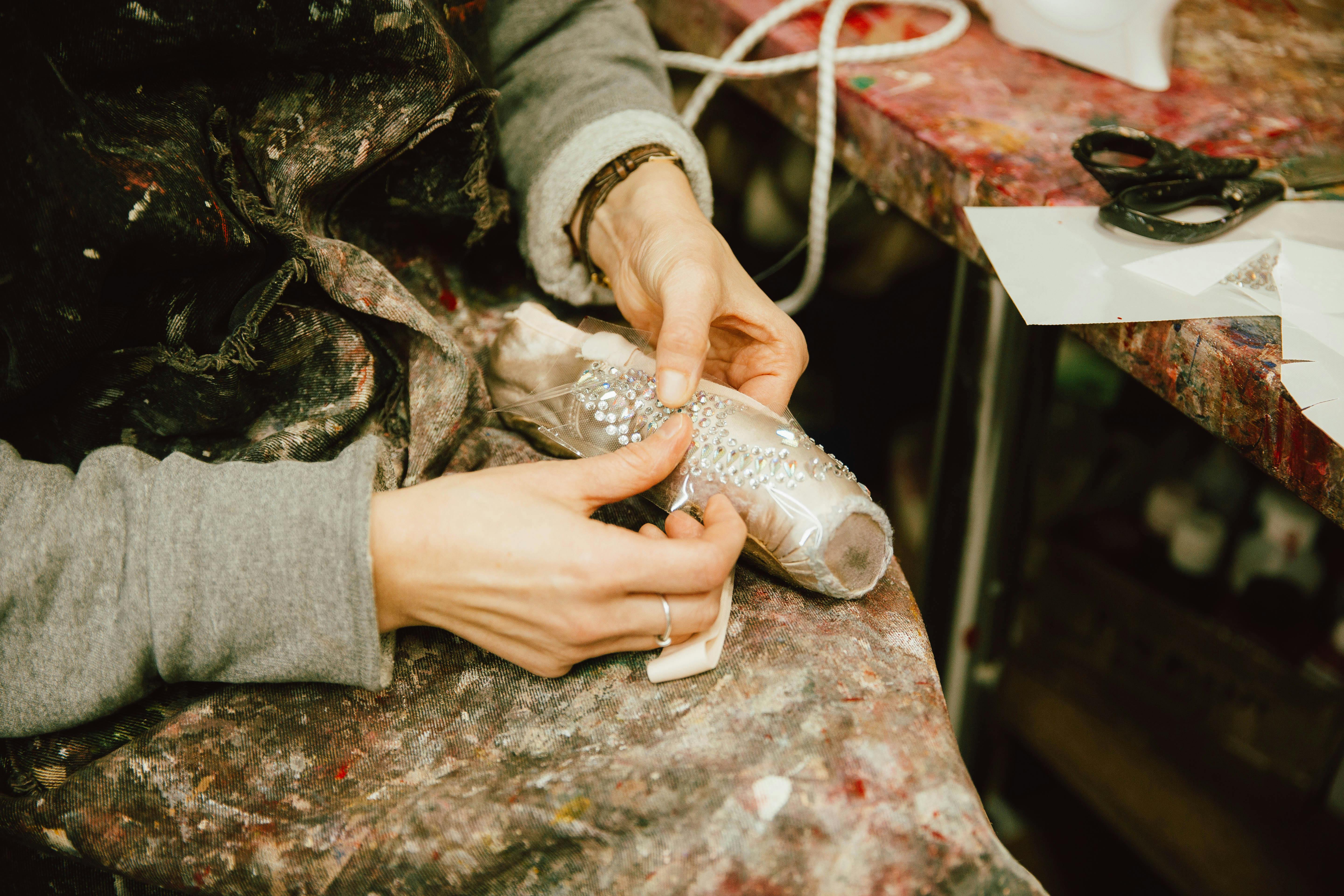 Close up of a worker applying clear sparkly rhinestones to a point shoe in the Royal Opera House ballet shoe workroom.