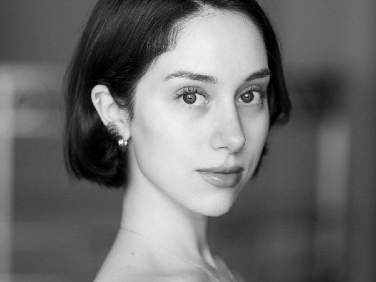 Black and white portrait of Royal Ballet dancer Ginevra Zambon. She has a dark bob that is tucked behind one ear and wears an off the shoulder black leotard.