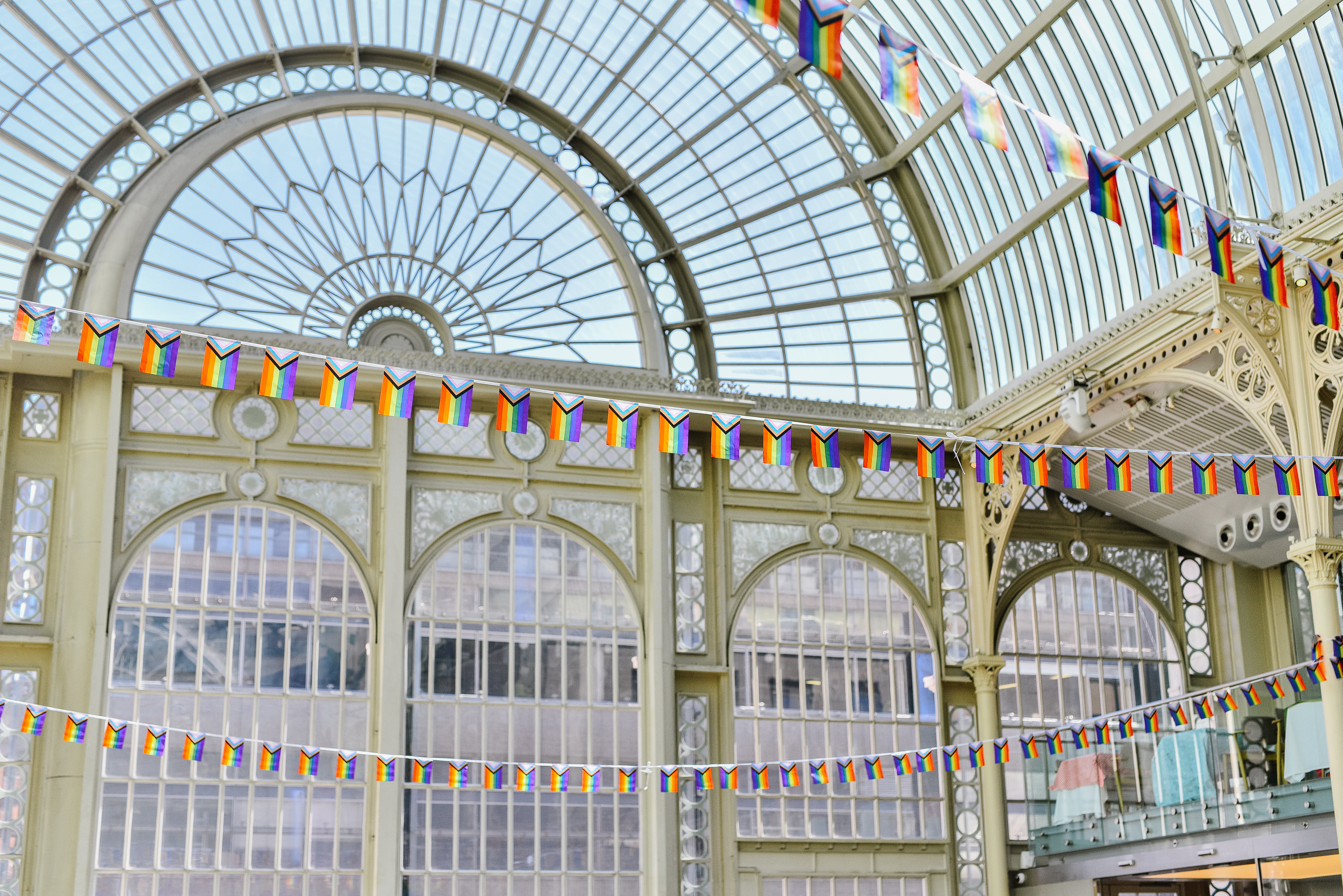 Pride flags hanging from the balconies of Paul Hamlyn Hall, adding vibrant colours to the architectural details of the space.