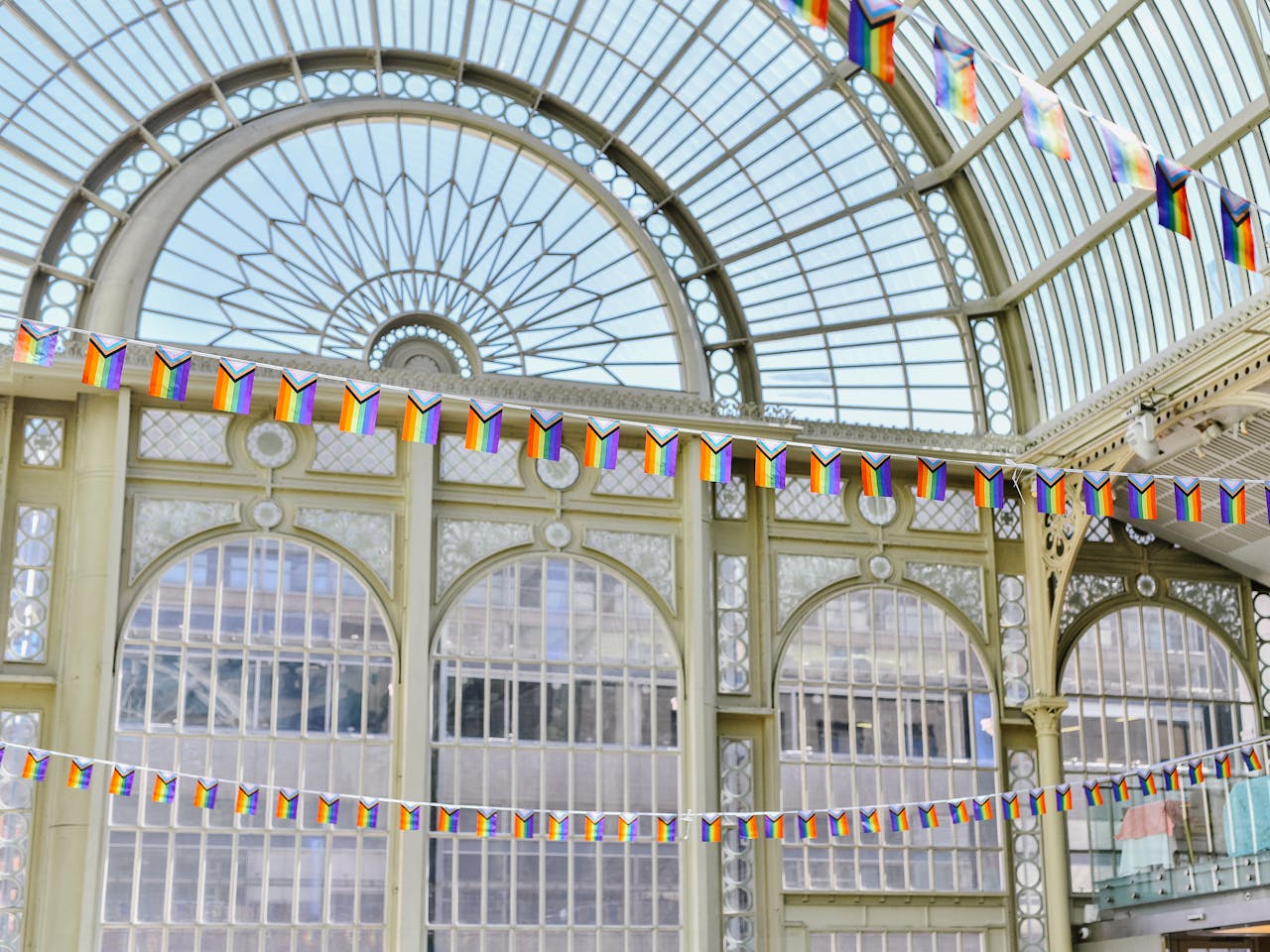 Pride flags hanging from the balconies of Paul Hamlyn Hall, adding vibrant colours to the architectural details of the space.