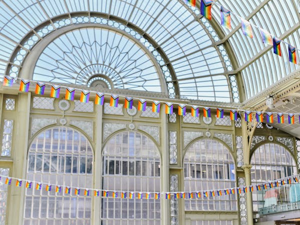 Pride flags hanging from the balconies of Paul Hamlyn Hall, adding vibrant colours to the architectural details of the space.