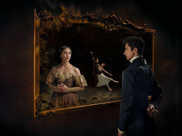 A person stares into a picture frame as another person in a decorative dress stares back. Behind them, two ballet dancers embrace.