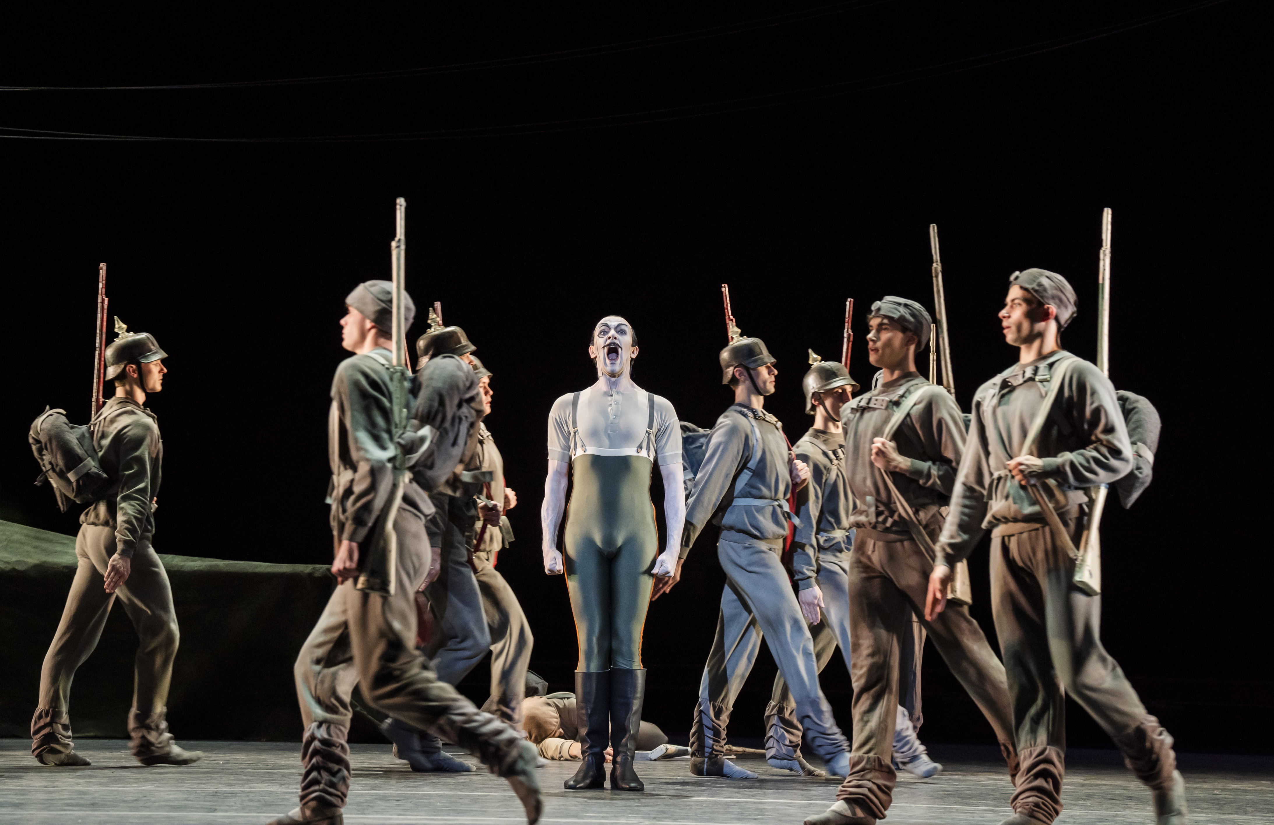 A man stands amid moving soldiers.