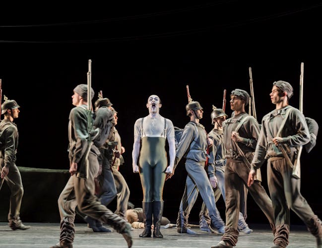 A man stands amid moving soldiers.