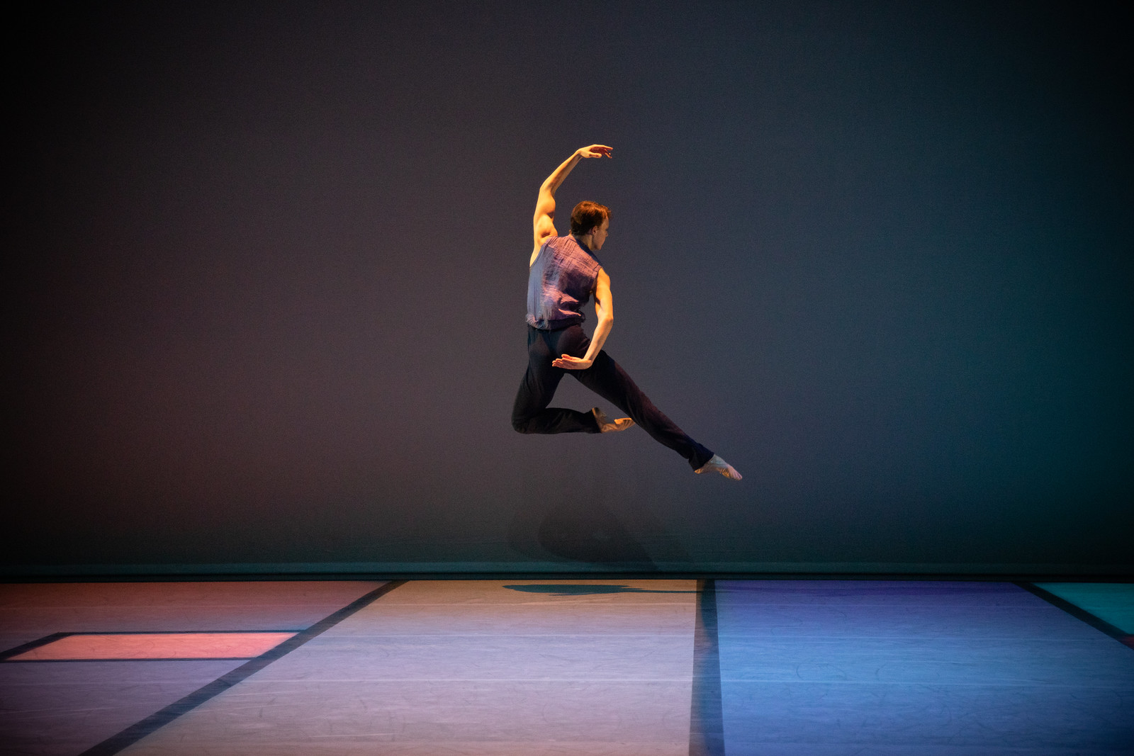 Ballet Dancer mid leap in front of blue background.