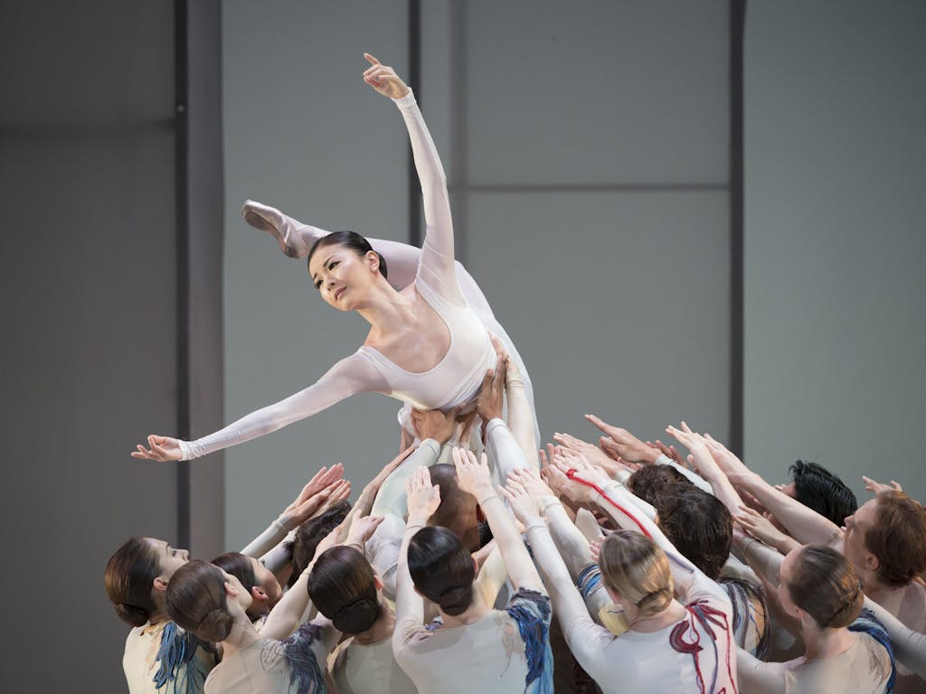 A group of Royal Ballet performers lifting another dancer above their head.