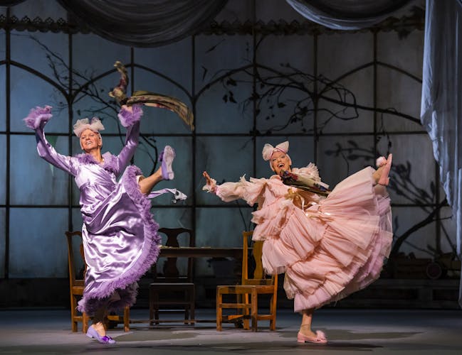 Gary Avis and Luca Acri performing in Cinderella. They are both wearing dresses and are lifting their legs in the air.