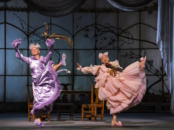 Gary Avis and Luca Acri performing in Cinderella. They are both wearing dresses and are lifting their legs in the air.