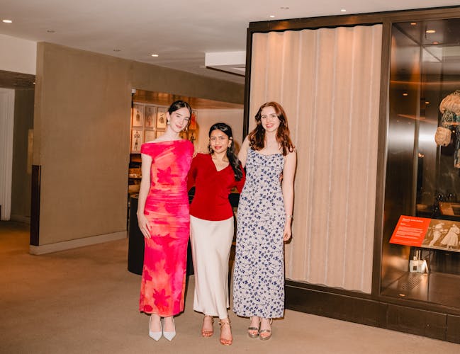 Three people pose in front of a cabinet displaying an ornate costume for the Royal Ballet's production of Romeo and Juliet. They are smiling at the camera.