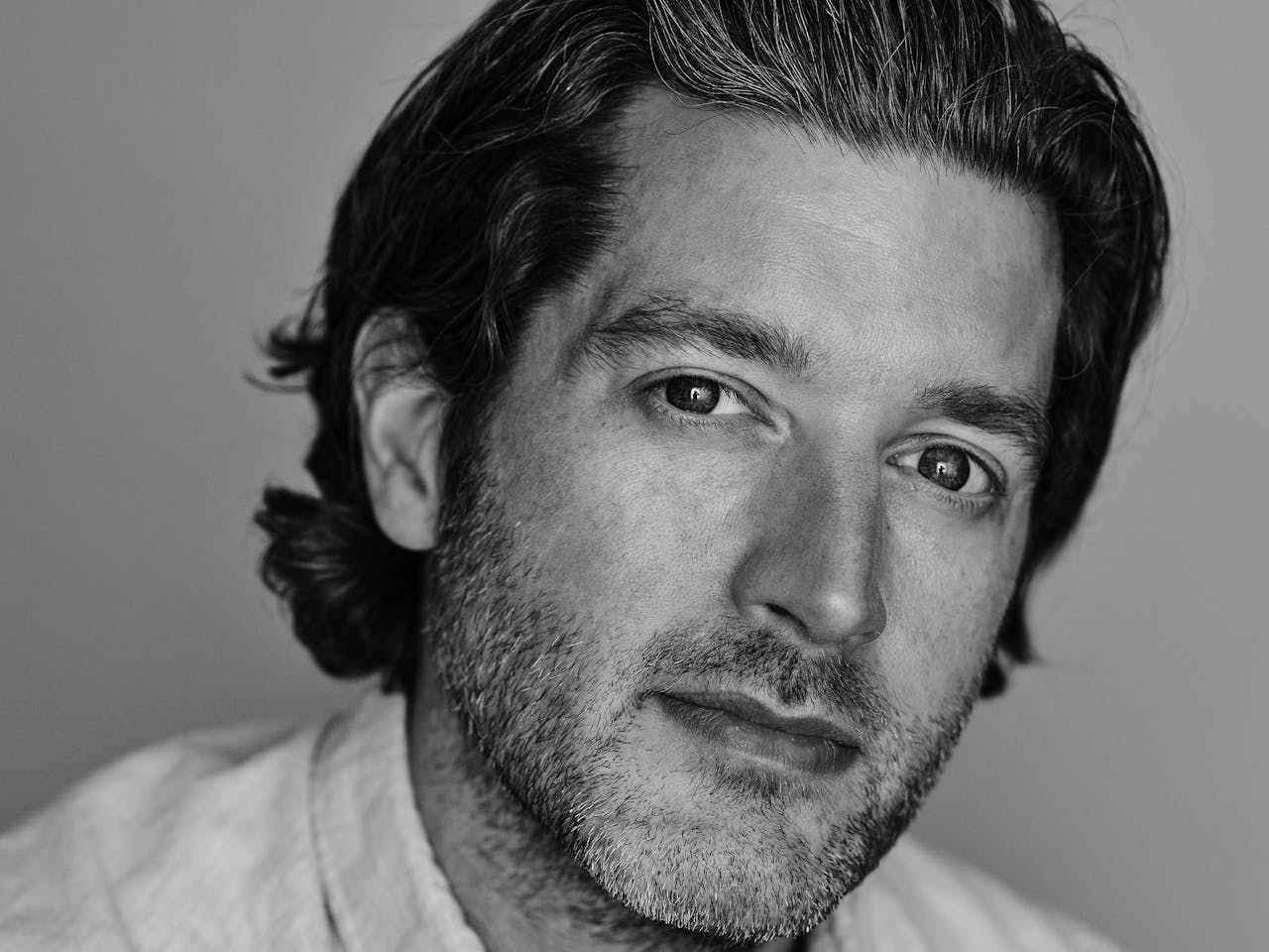 A black and white headshot of the video designer Duncan McLean. They wear a white shirt.
