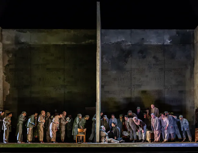 A group of people stand around a woman who is slumped against a wall.