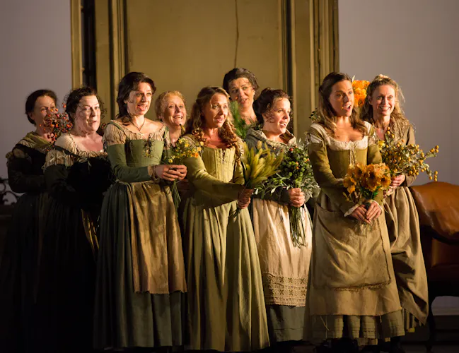 A group of women in green dresses holding bouquets of flowers and singing.
