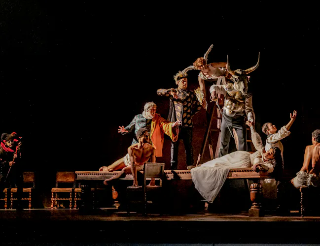 A tableau of a woman in white lying on a table as figures loom above her. There is a minotaur, an angel and a scholar.