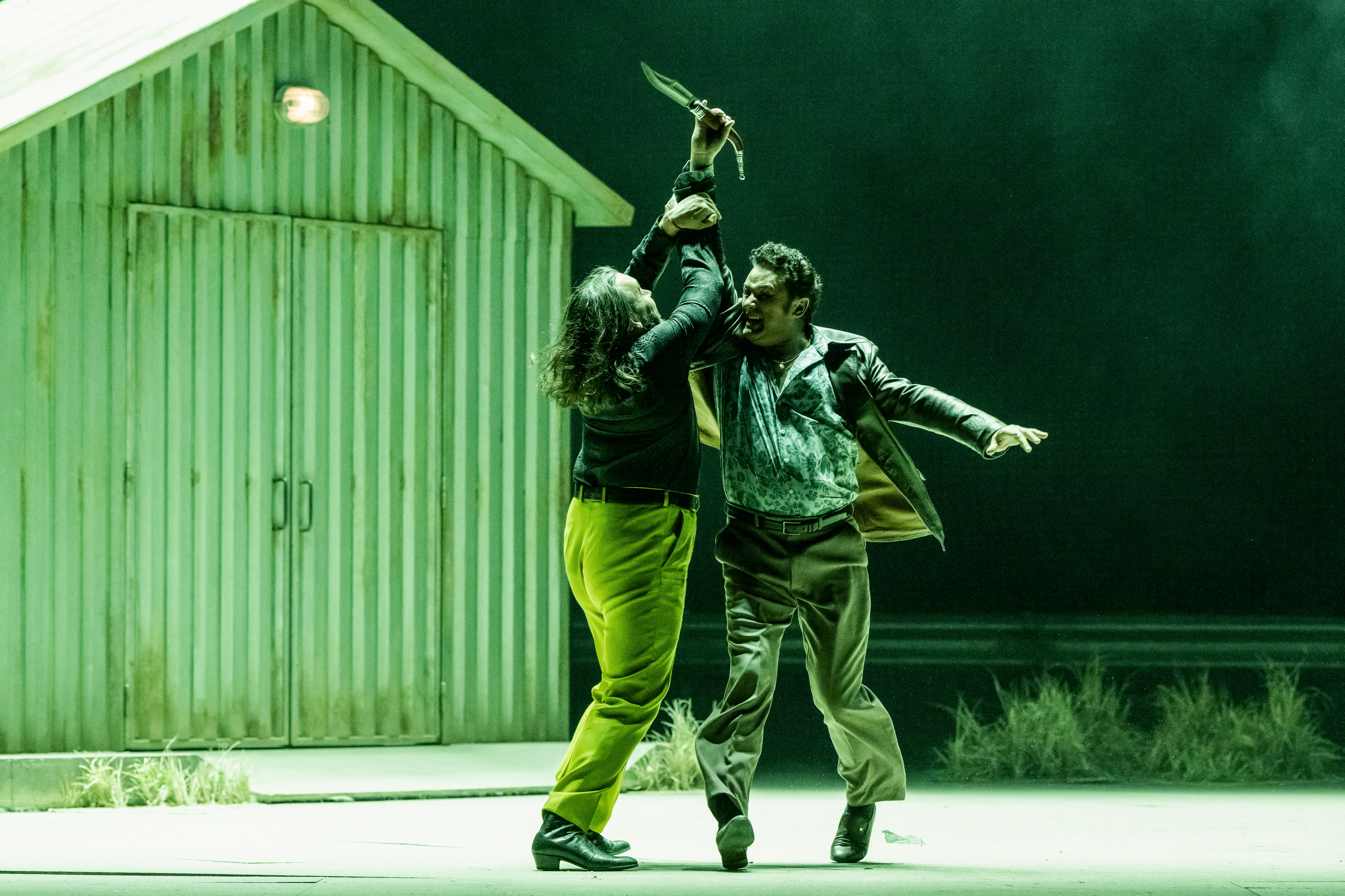 Two performers fight on stage with one raising a knife into the air. They are performing in The Royal Opera's production of Carmen. (6 of 7)