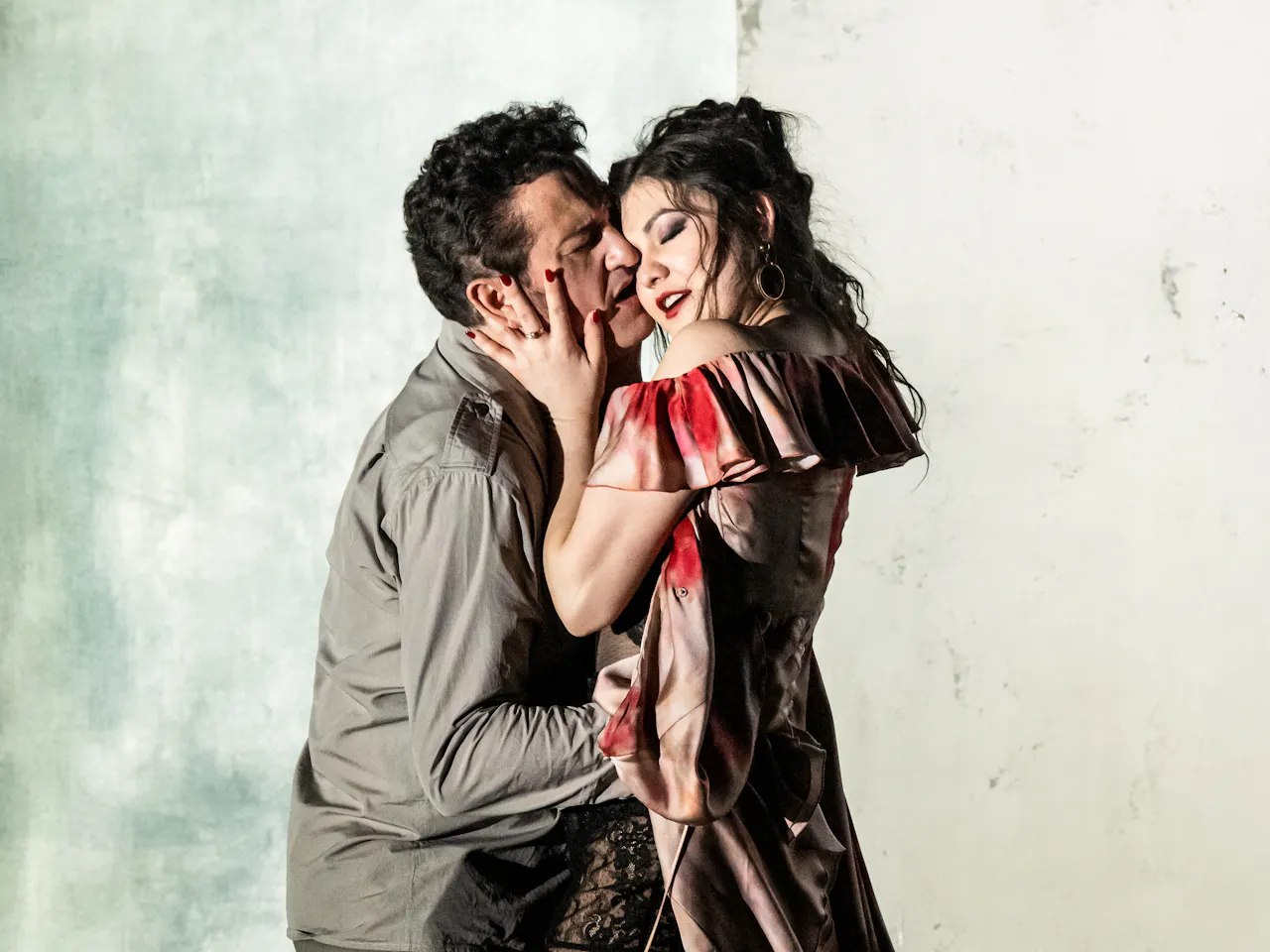 Two opera singers embrace passionately on stage. They are performing in The Royal Opera's production of Carmen.