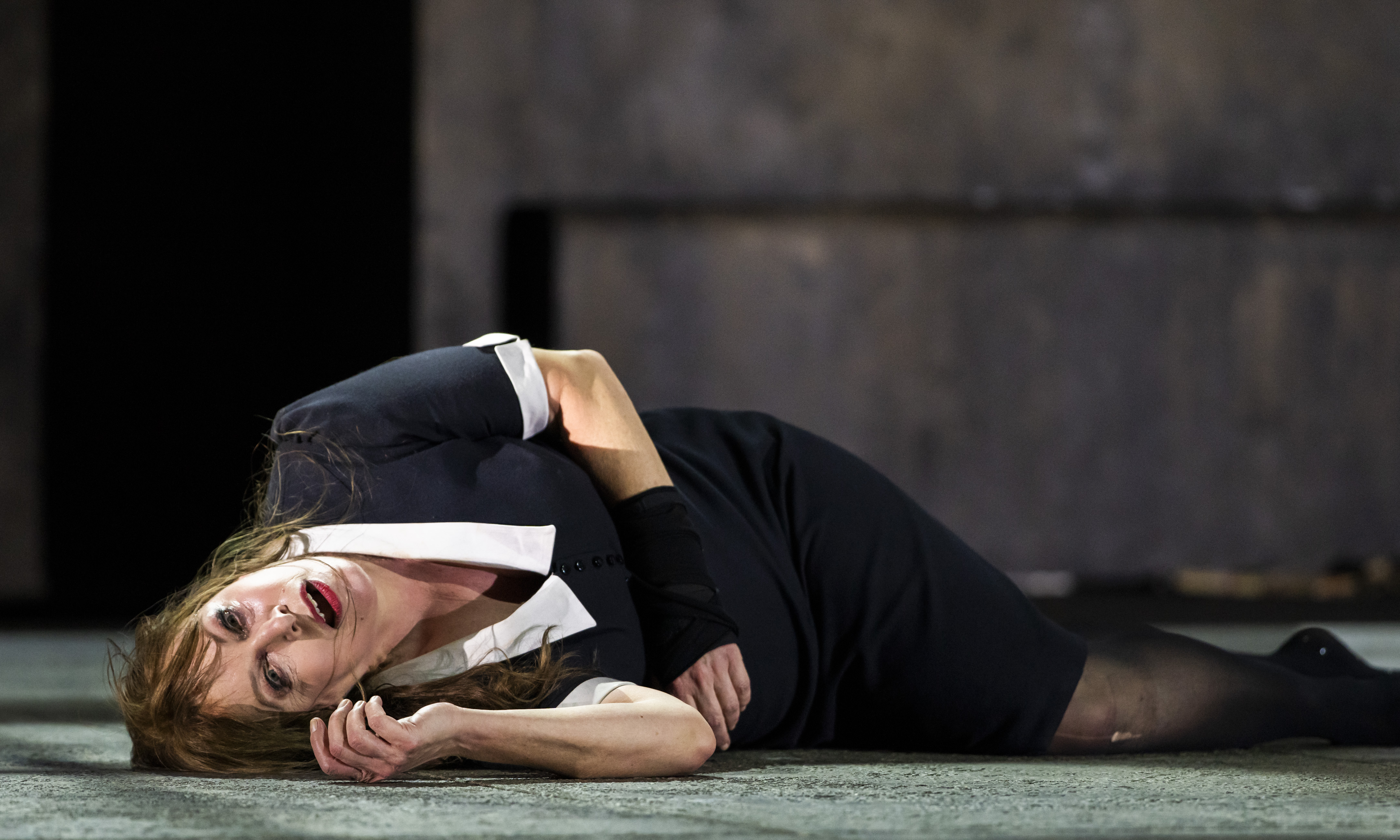 A performer wearing a black and white maids uniform lies on the stage looking out, almost in pain or turmoil. (5 of 5)