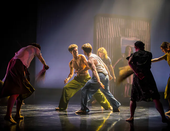 Several ballet dancers perform on stage in a dimly lit space with haze. (1 of 3)