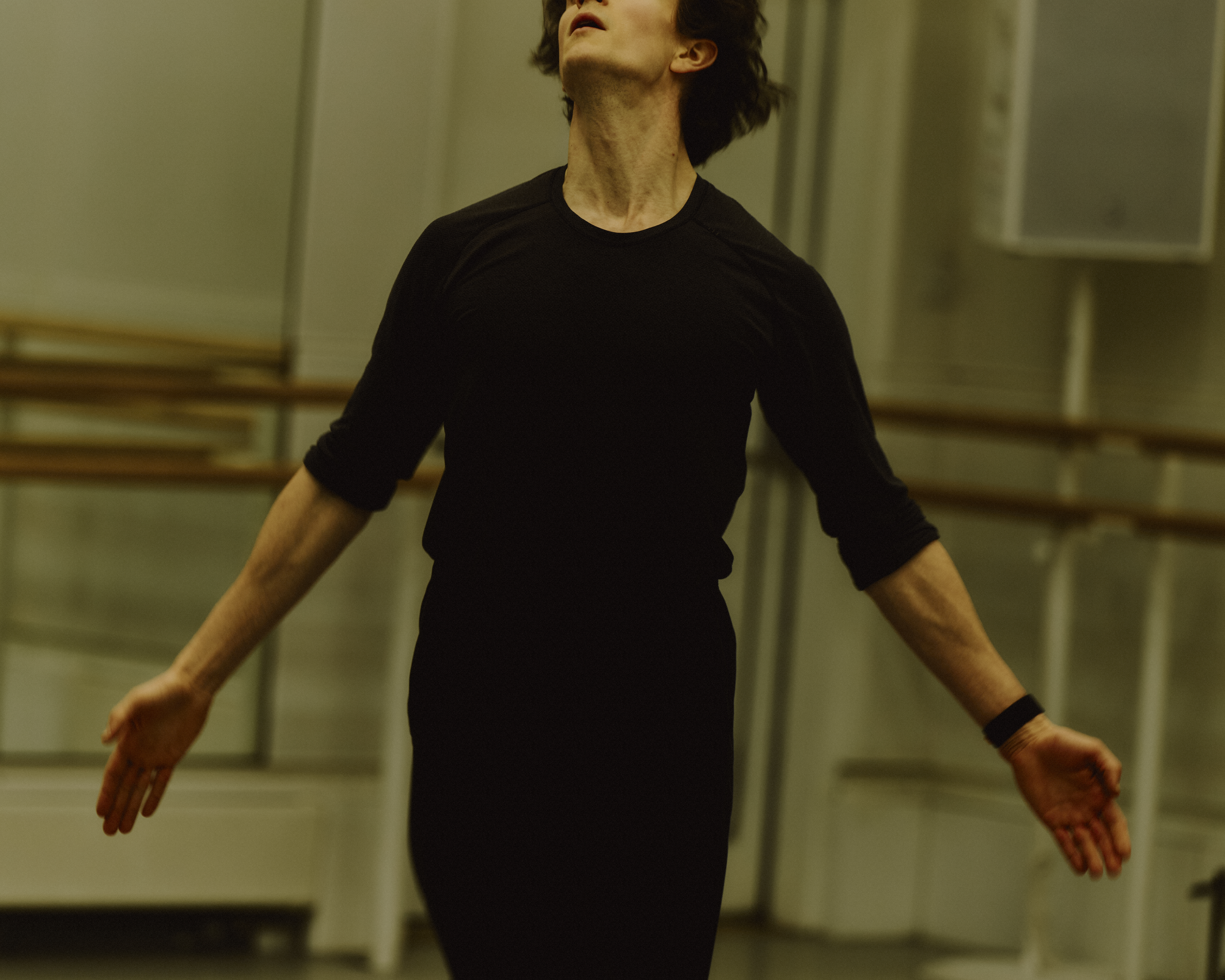 The Royal Ballet dancer William Bracewell performs in a well-lit dance studio in rehearsals with his arms stretched outwards. (3 of 4)