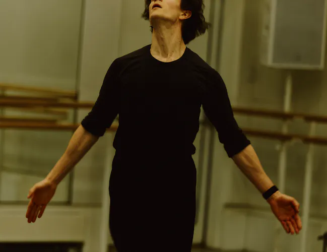 The Royal Ballet dancer William Bracewell performs in a well-lit dance studio in rehearsals with his arms stretched outwards. (3 of 4)