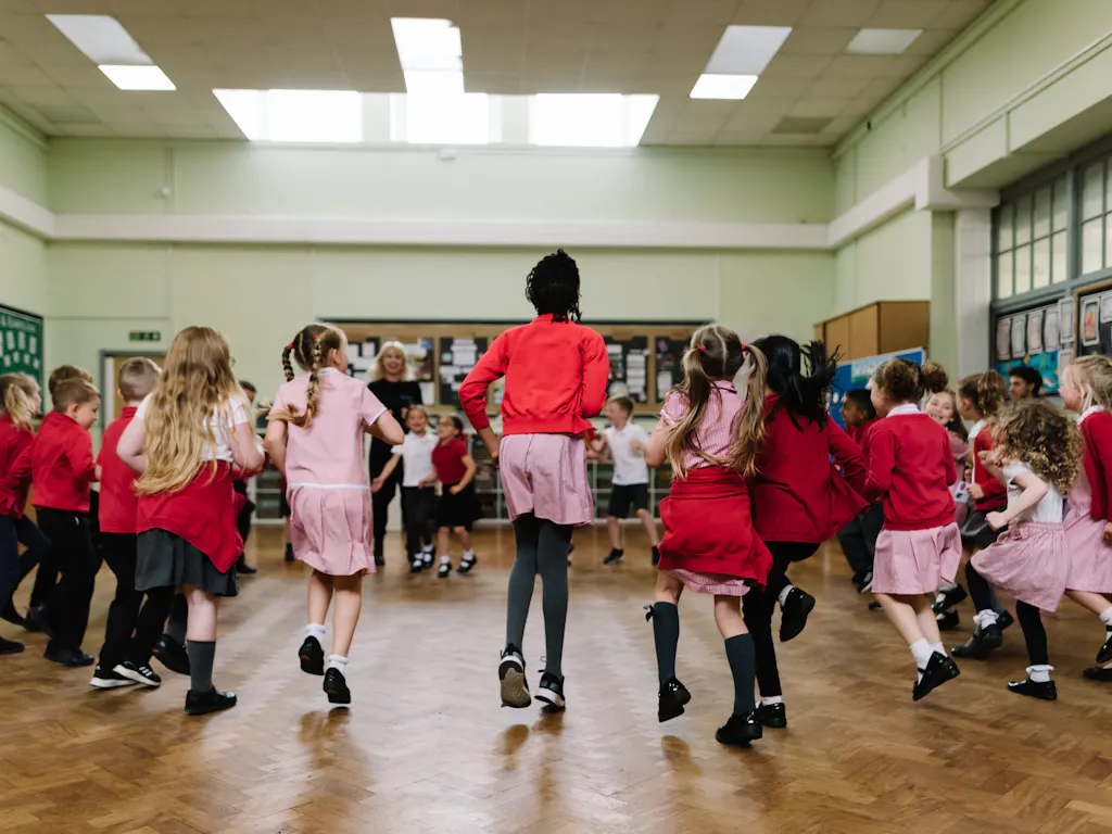 A group of school children dance in a circle as part of the Royal Ballet and Opera's Create and Dance programme.