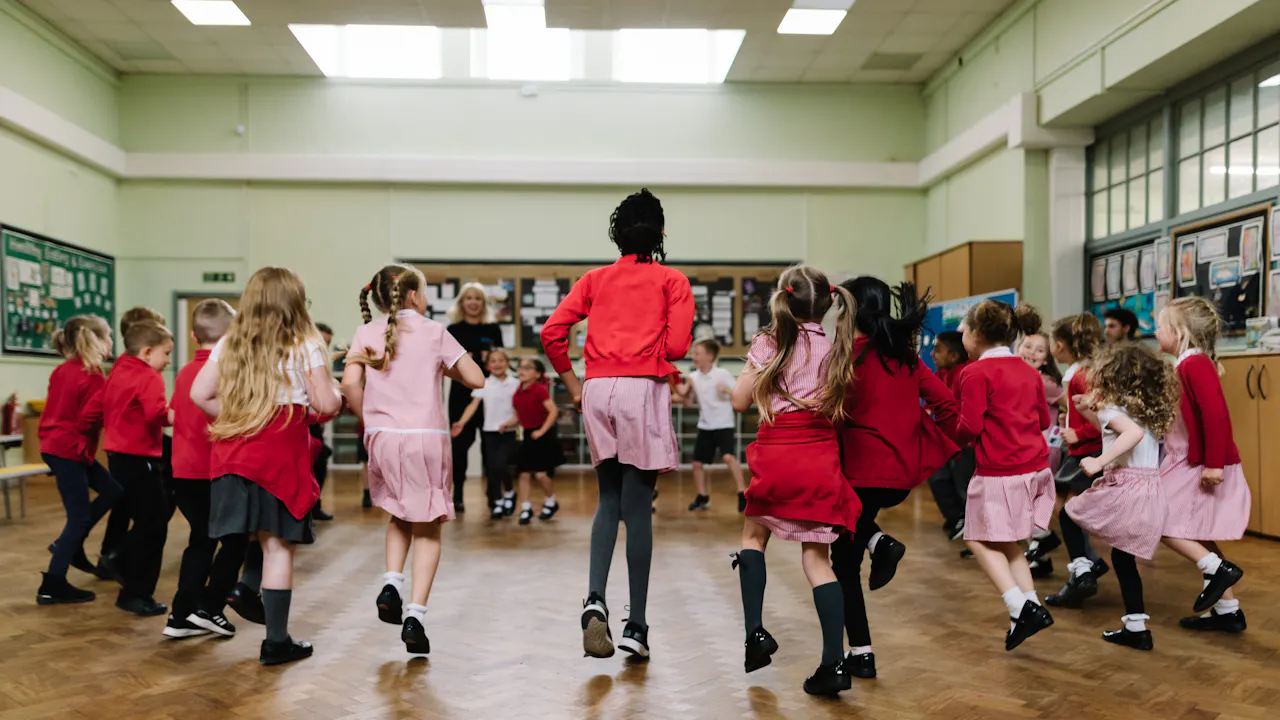 A group of school children dance in a circle as part of the Royal Ballet and Opera's Create and Dance programme.